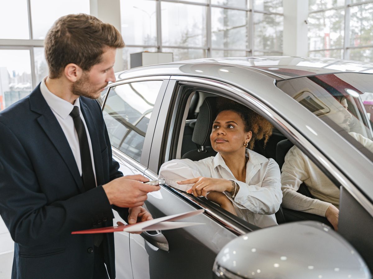 Ein Verkäufer übergibt einer Kundin im Autohaus den Schlüssel ihres Autos