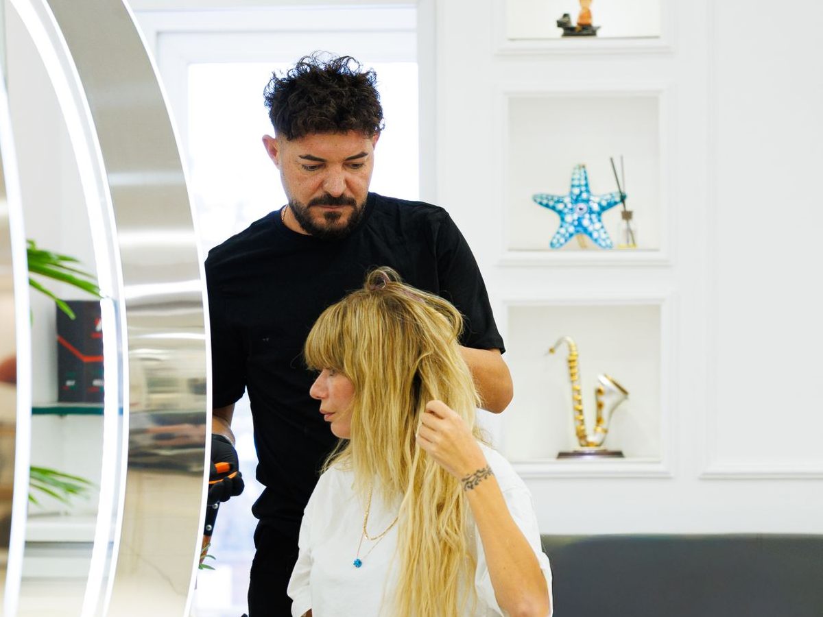 Ein Friseur stylt einer Kundin in einem hellen Salon die Haare